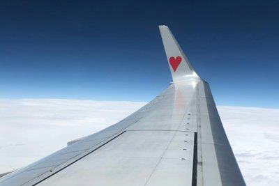Foto von Flugzeug-Flügel mit kleinem roten Herz über den Wolken