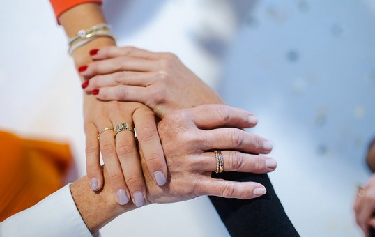 Foto von drei Händen, die übereinander liegen und sich gegenseitig halten